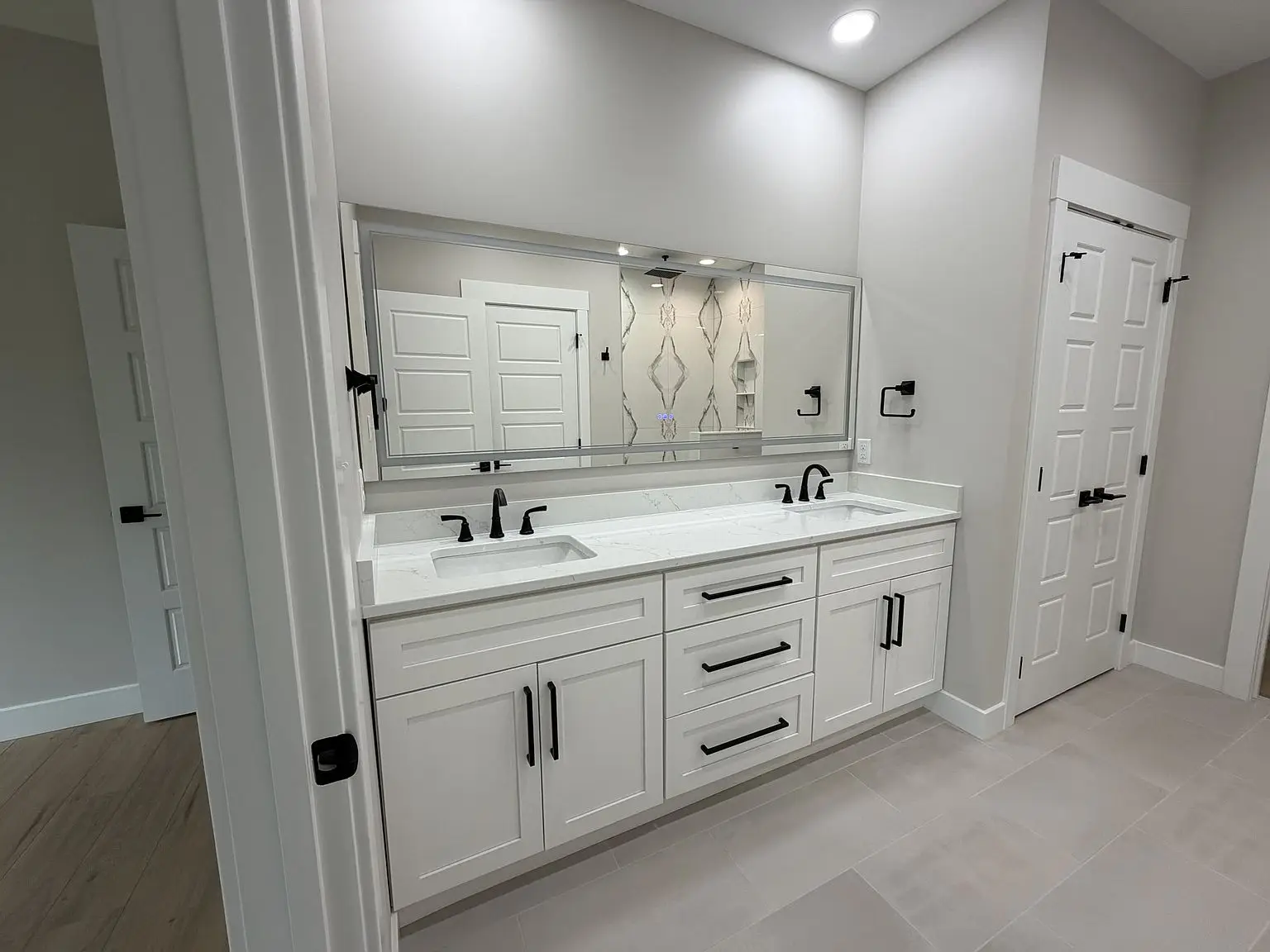 Double sink vanity with white cabinets in the Robin floor plan, modern bath and black fixtures.