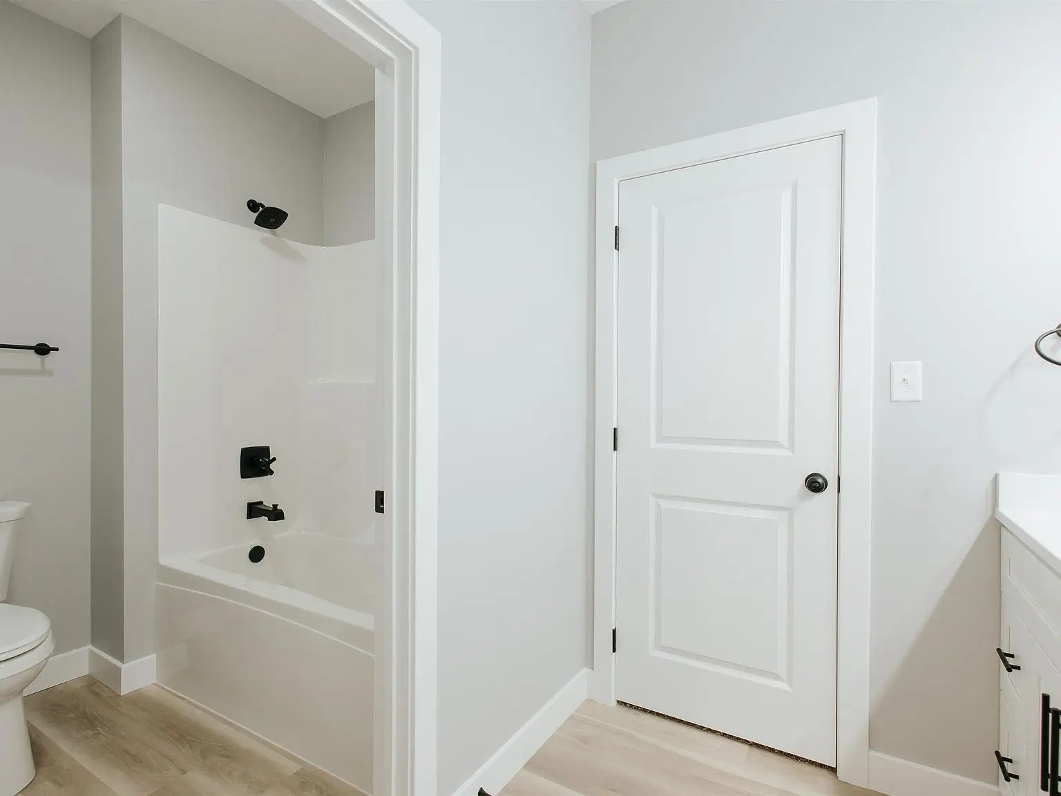 Bathroom features Eleanor floor plan with white tub, black fixtures, and light wood flooring.