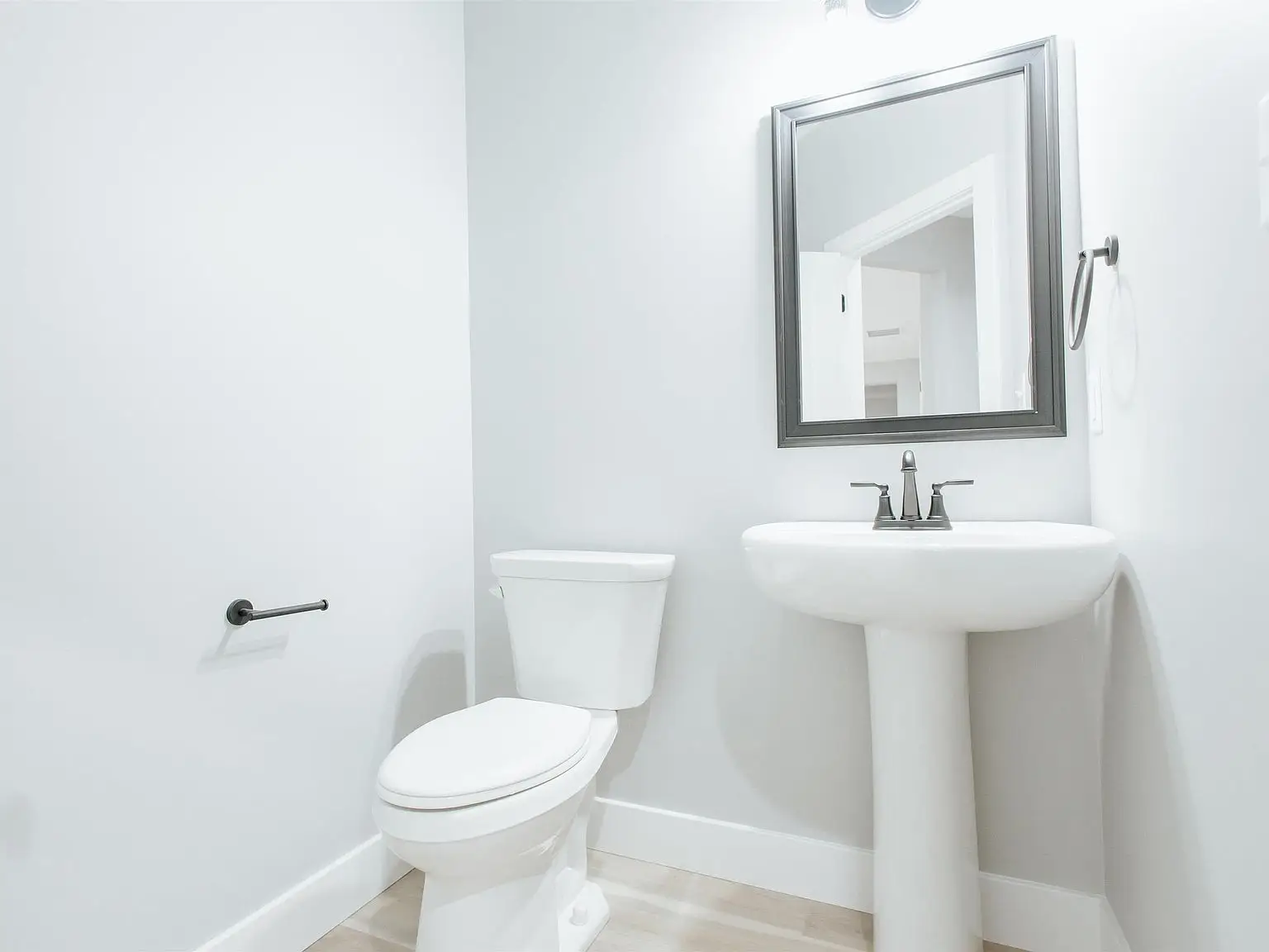 Bright white bathroom with pedestal sink, mirror, and Eleanor floor plan at Chris Brown Homes.