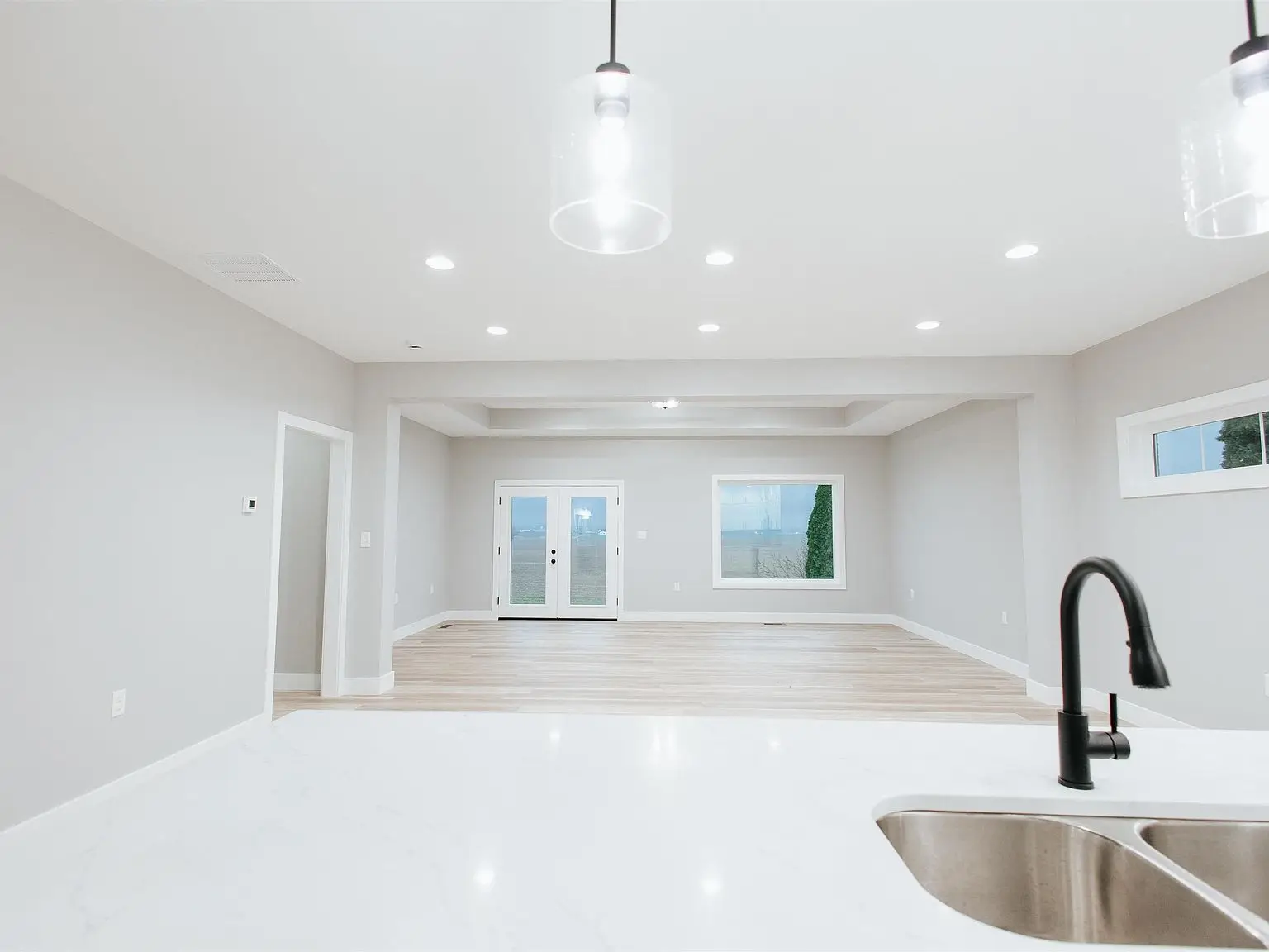 Modern open-concept room in the Eleanor home with white walls, wood floors, and black faucet.