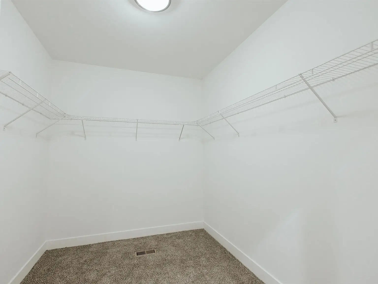Empty walk-in closet with white walls, carpet, wire shelving—part of the Eleanor floor plan.