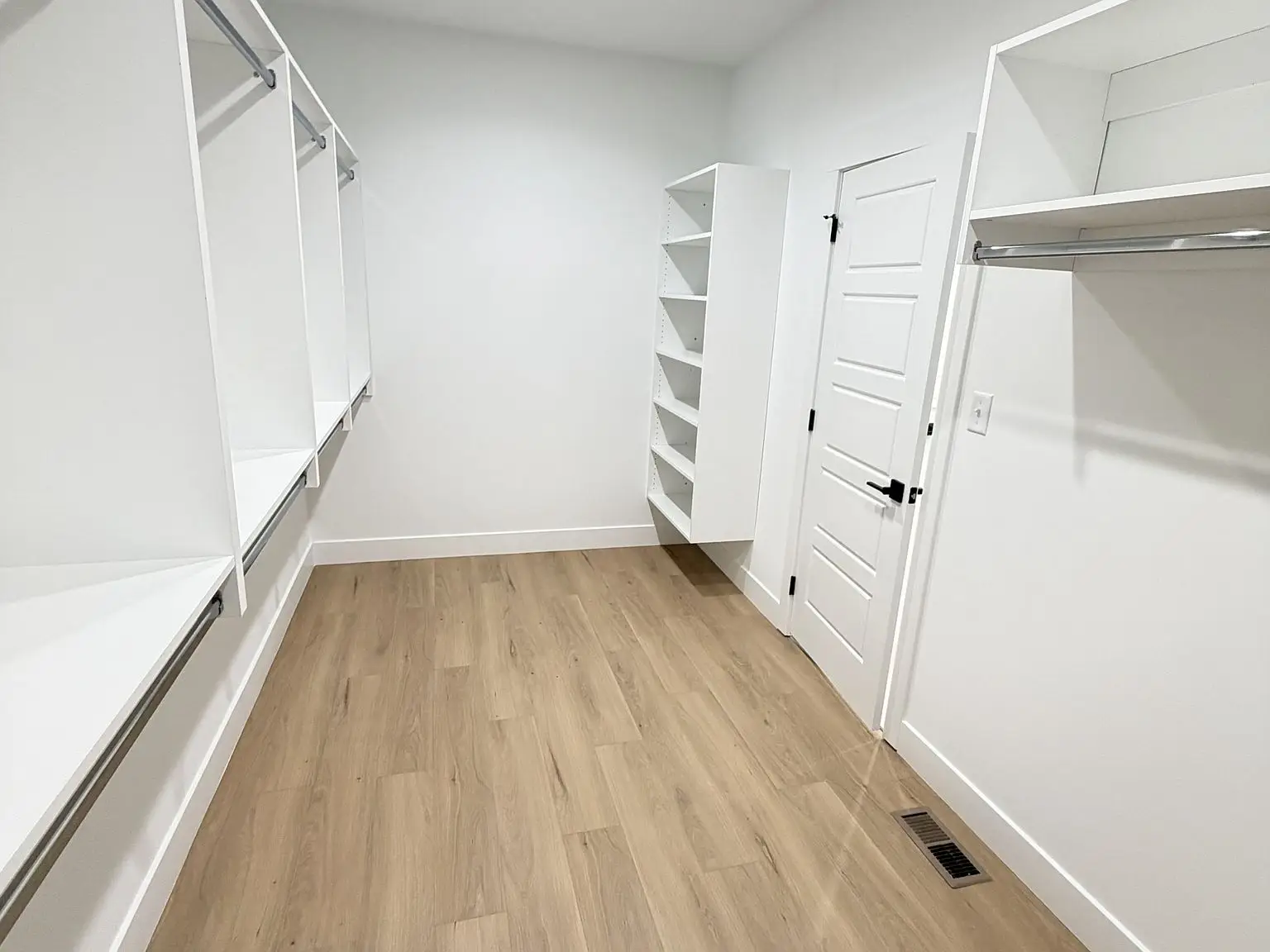 Empty walk-in closet with white shelves, Robin floor plan, and light wood flooring.