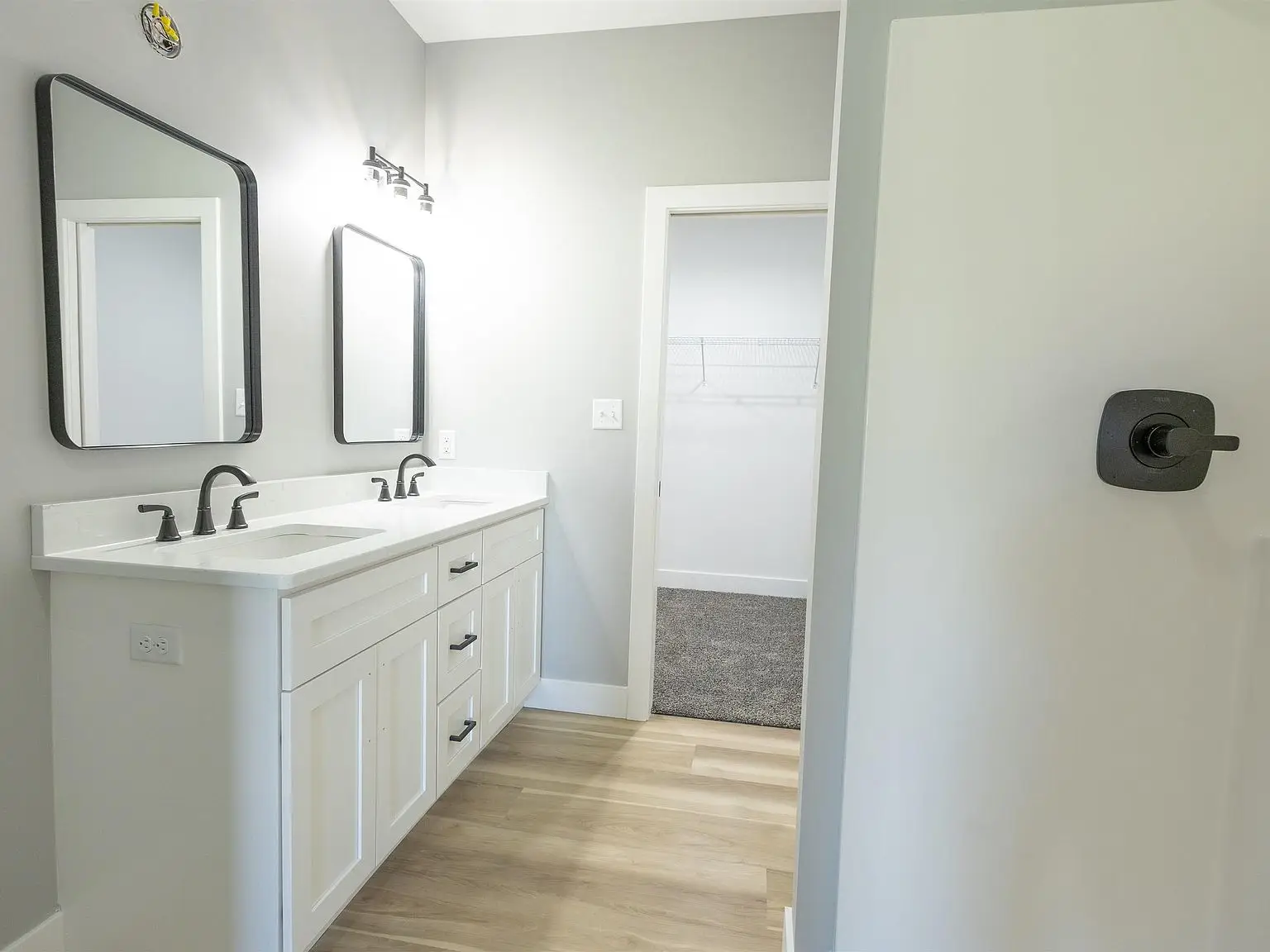 Bathroom in the Kirkwood floor plan with double sink vanity, two mirrors, and closet view.