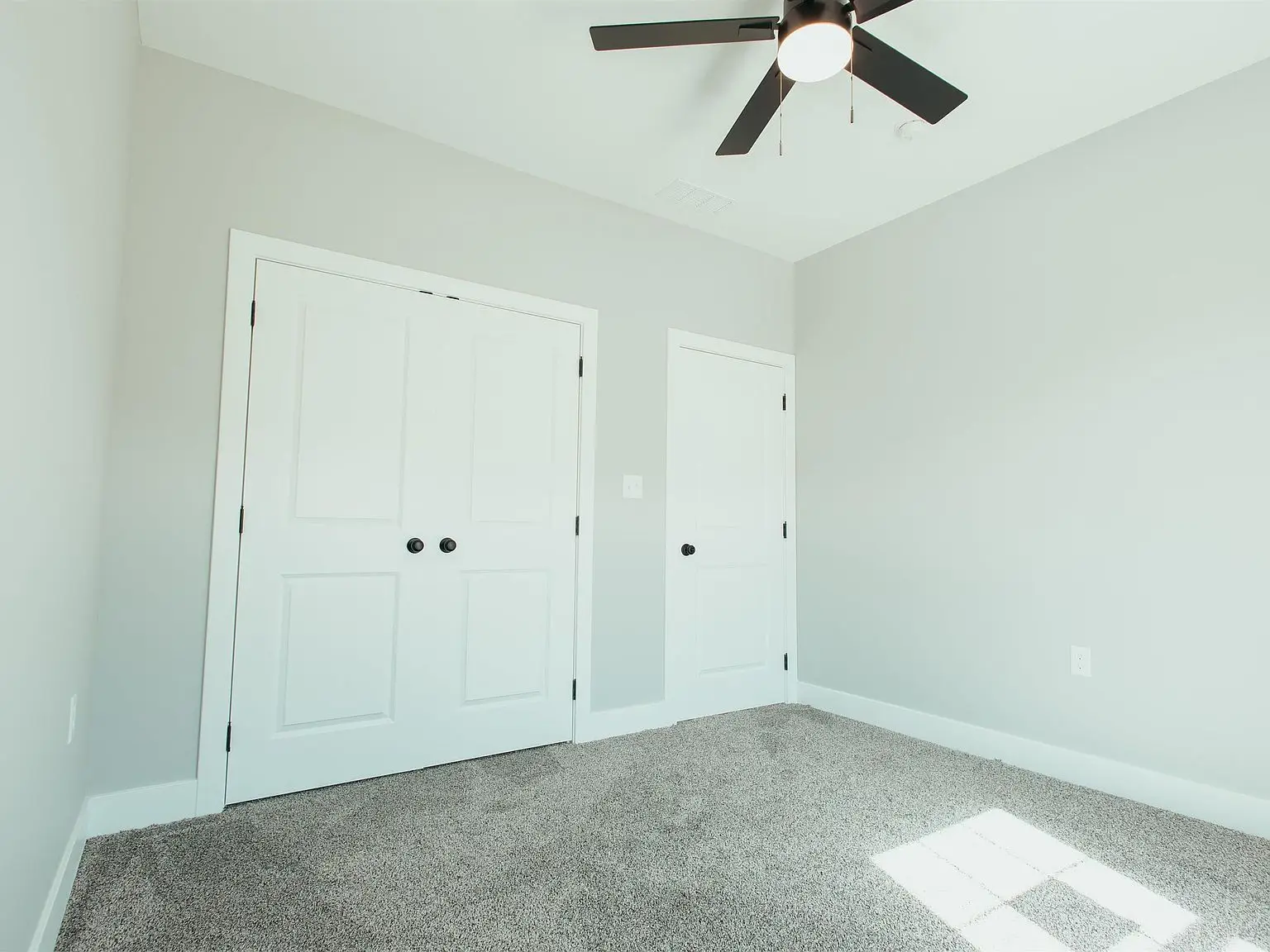 Empty room with gray carpet, white walls, and two doors in Chris Brown Homes 1624 Eli Dr.