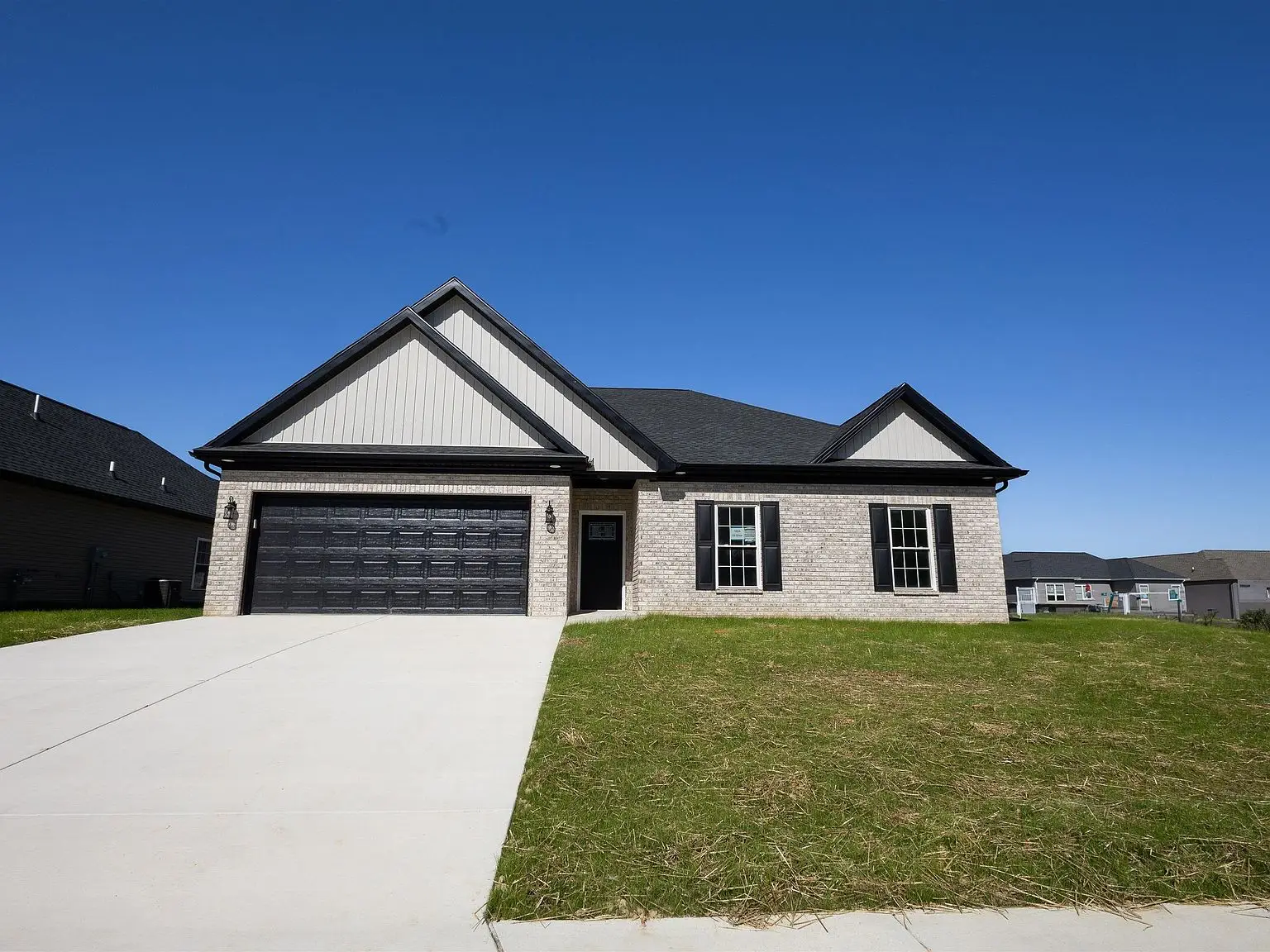 Single-story Kirkwood with brick exterior, black garage doors, and a concrete driveway.