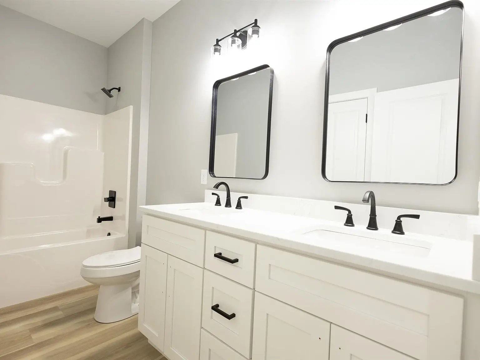Modern bathroom in the Kirkwood floor plan with double sinks, white cabinets, and a bathtub.