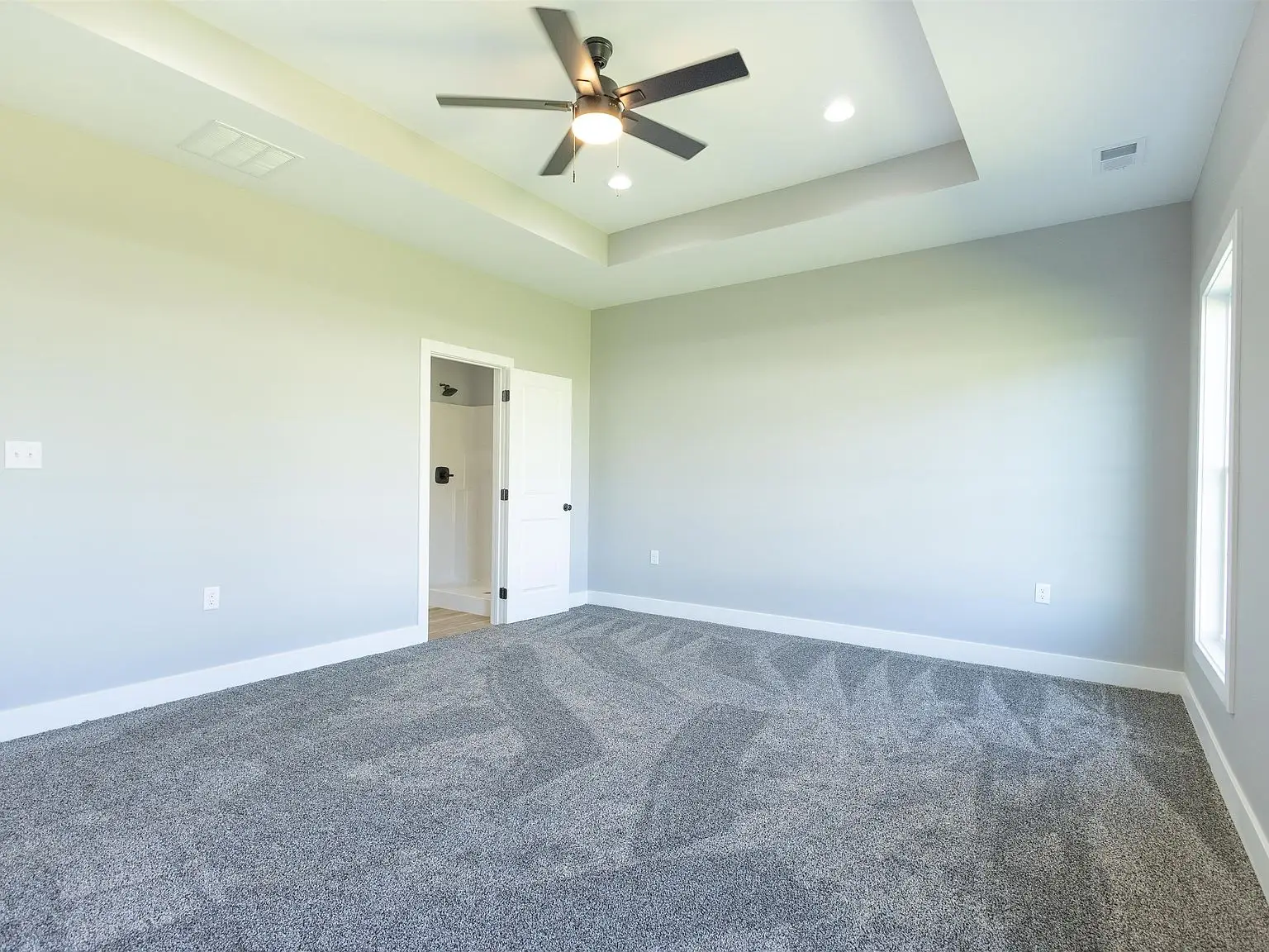 Empty room with gray carpet, white walls, and ceiling fan in the Kirkwood floor plan.