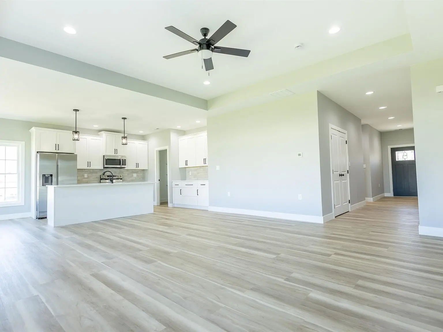 Spacious Kirkwood floor plan with light wood floors and a kitchen with white cabinets.