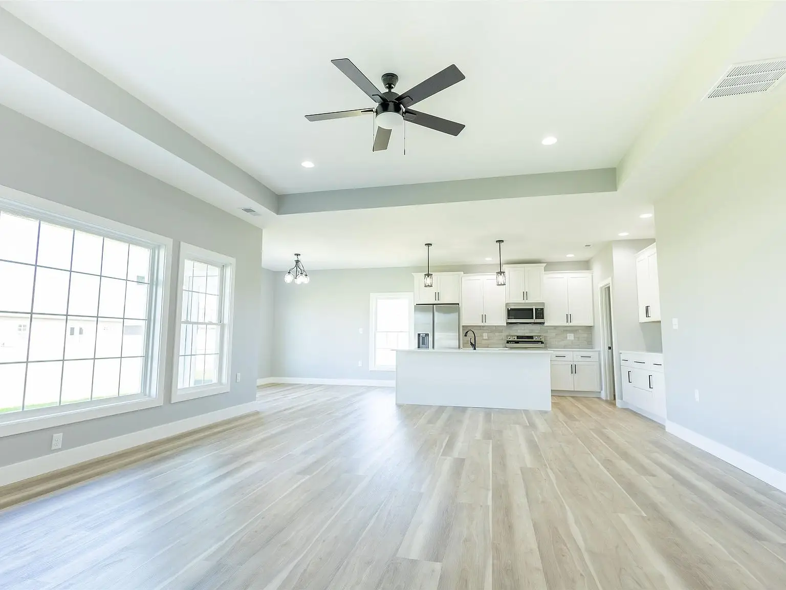 Bright, empty modern kitchen and living space with Kirkwood floor plan and wood floors.