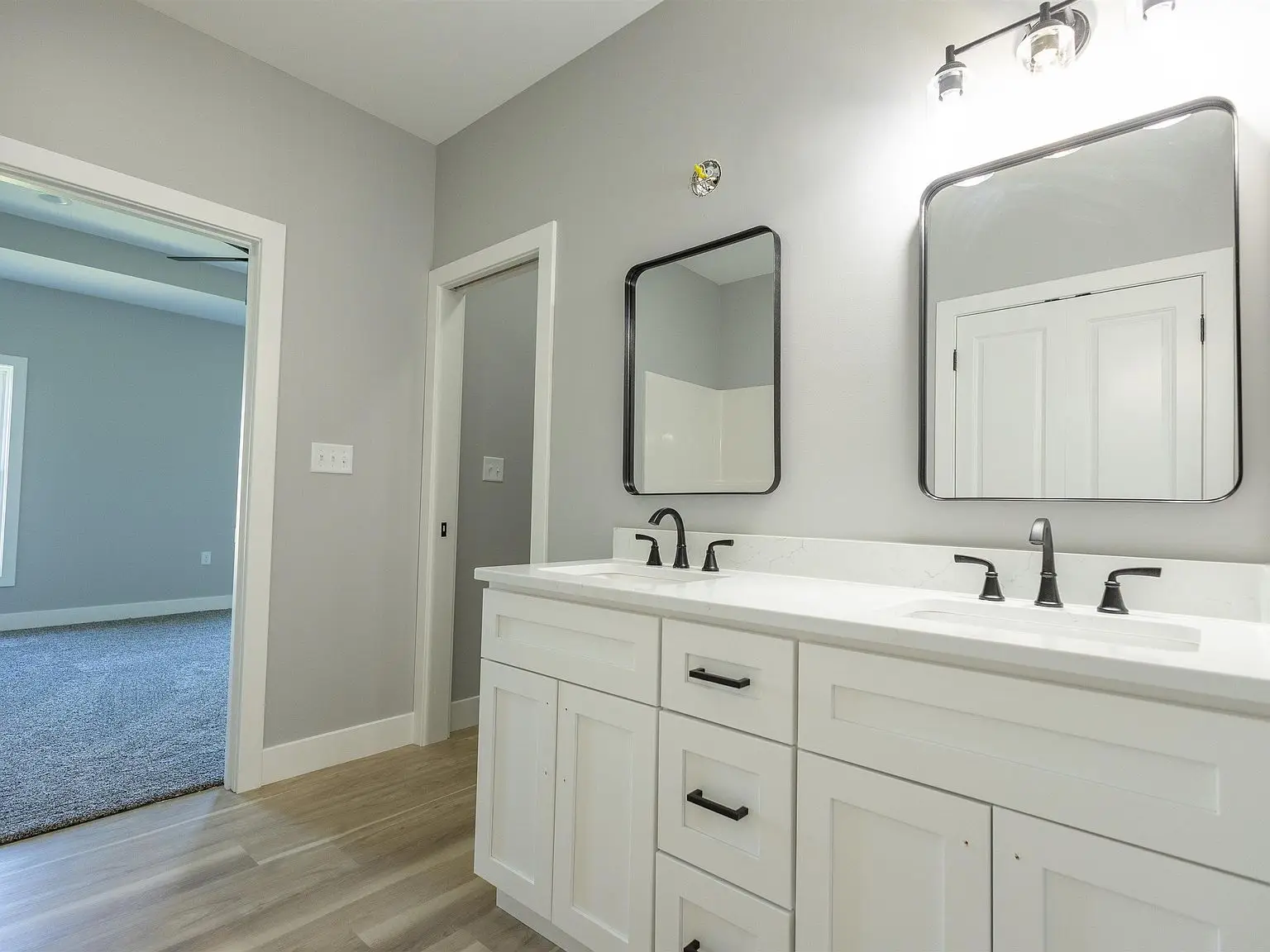 Modern bathroom in the Kirkwood floor plan with double sinks, white cabinets, and black fixtures.