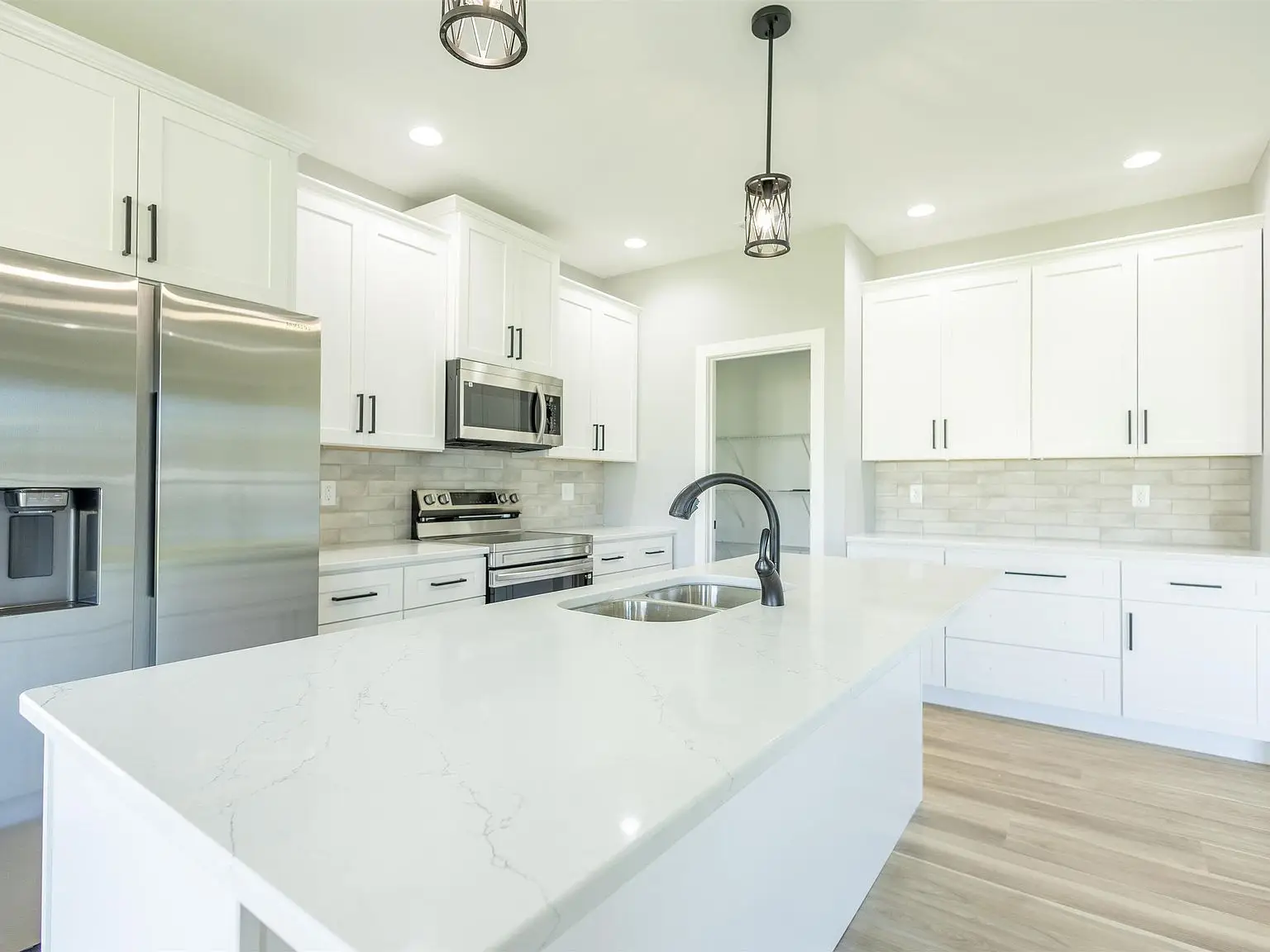 Modern kitchen with white cabinets, island sink, and Kirkwood floor plan by Chris Brown Homes.