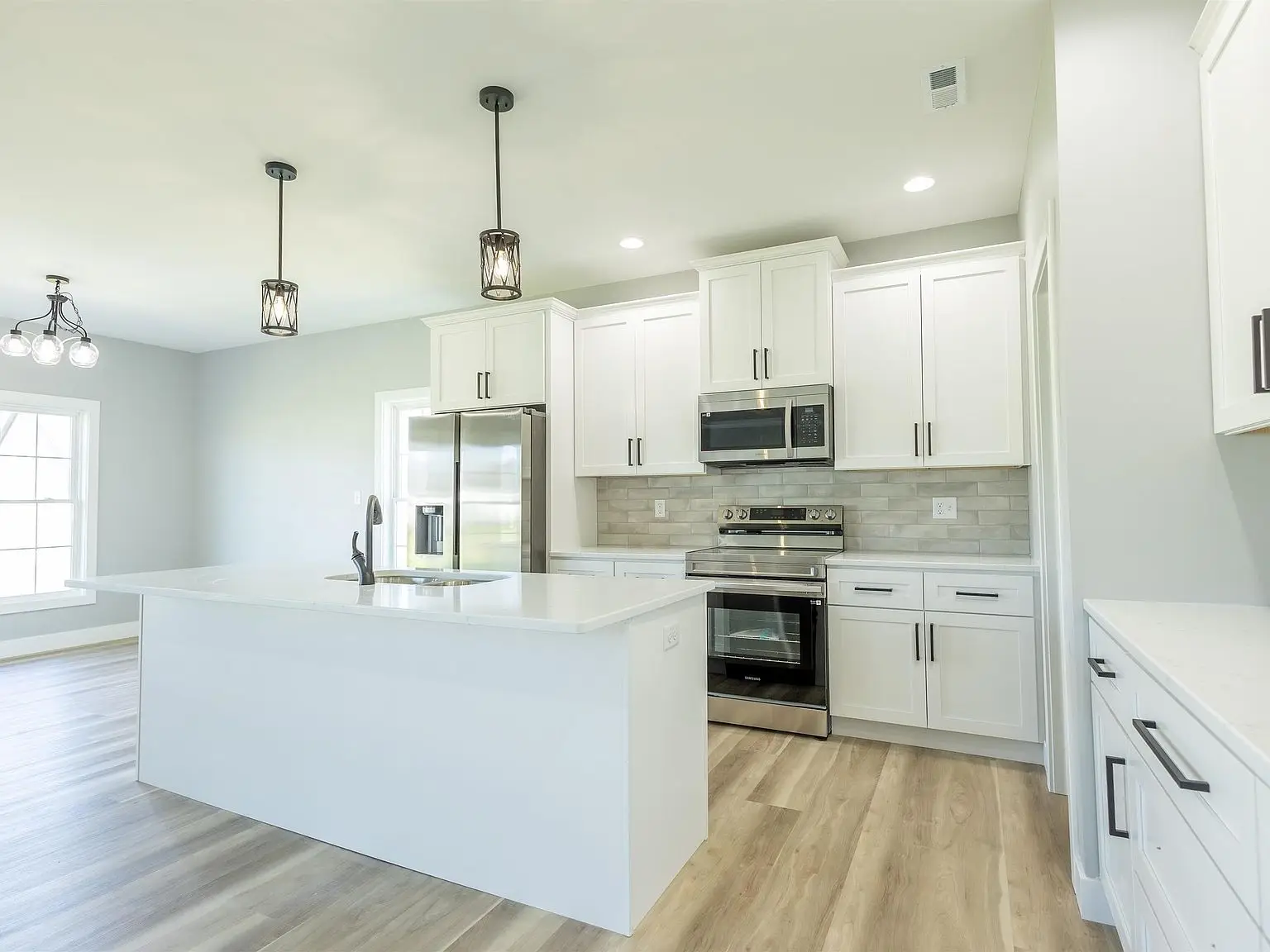 Modern kitchen in the Kirkwood floor plan with white cabinets, island, and wood flooring.