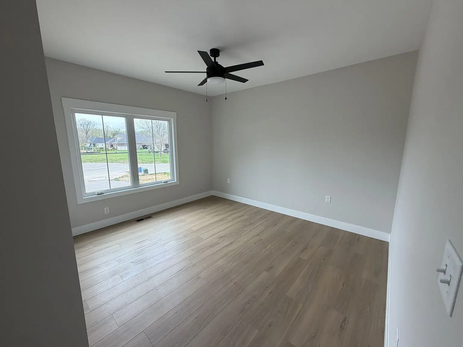 Empty room with wood floor, white walls, ceiling fan, and a large Robin floor plan window.