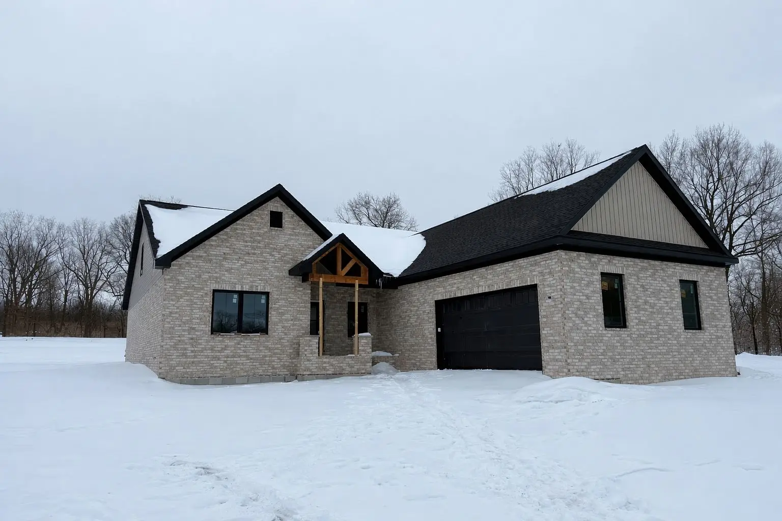 Modern brick house with black trim, Robin floor plan by Chris Brown Homes, in snowy landscape.