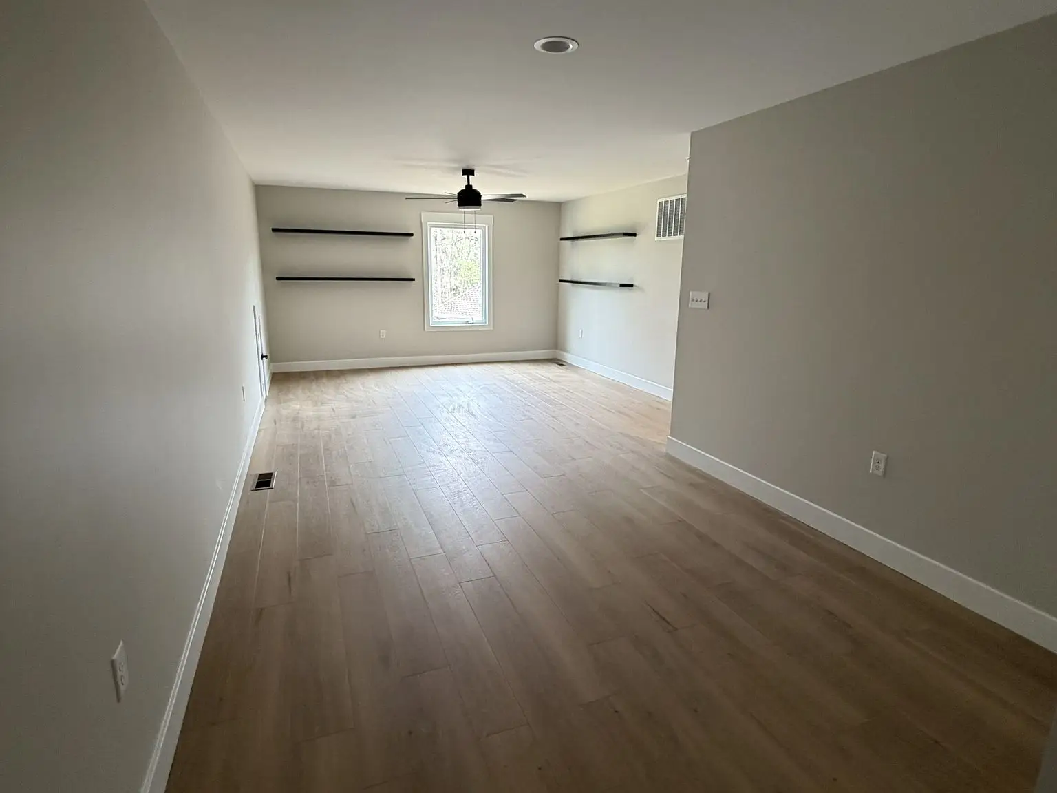 Empty room with light wood floors, white walls, and black shelves in a Robin floor plan.