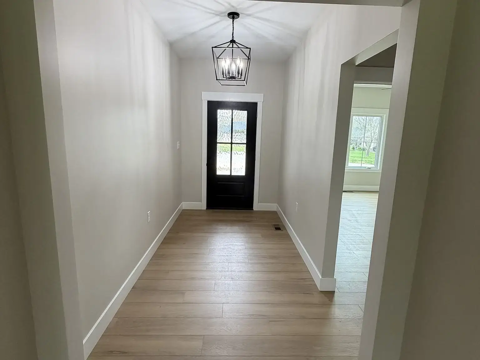 Hallway with wood floor, black door, white walls—features of the Robin floor plan.