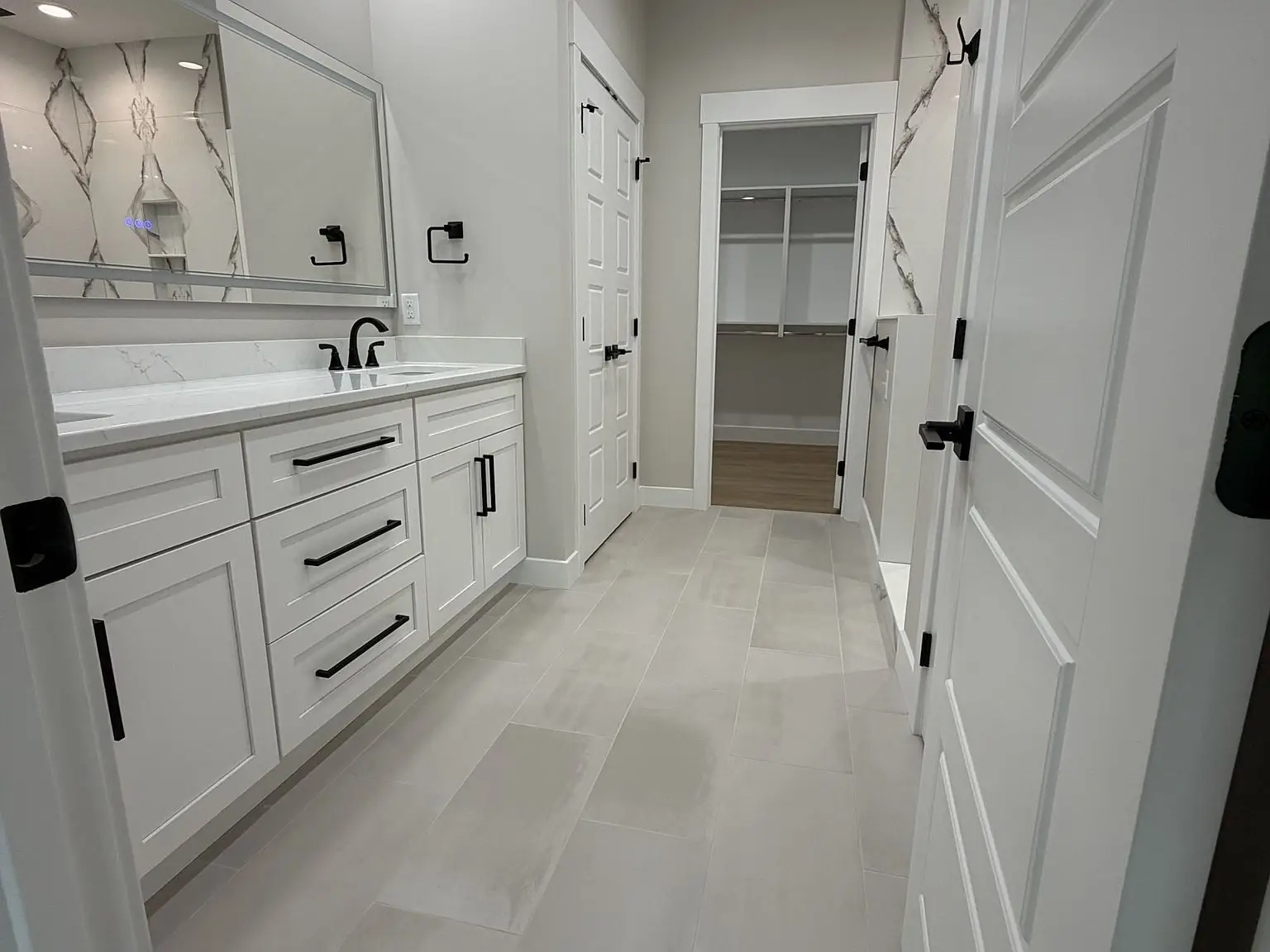 Modern bathroom in the Robin floor plan with white cabinets, double sink, walk-in closet view.