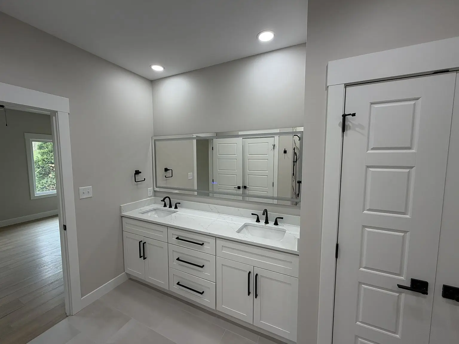Modern bathroom in the Robin floor plan features double sinks, white cabinets, and large mirror.