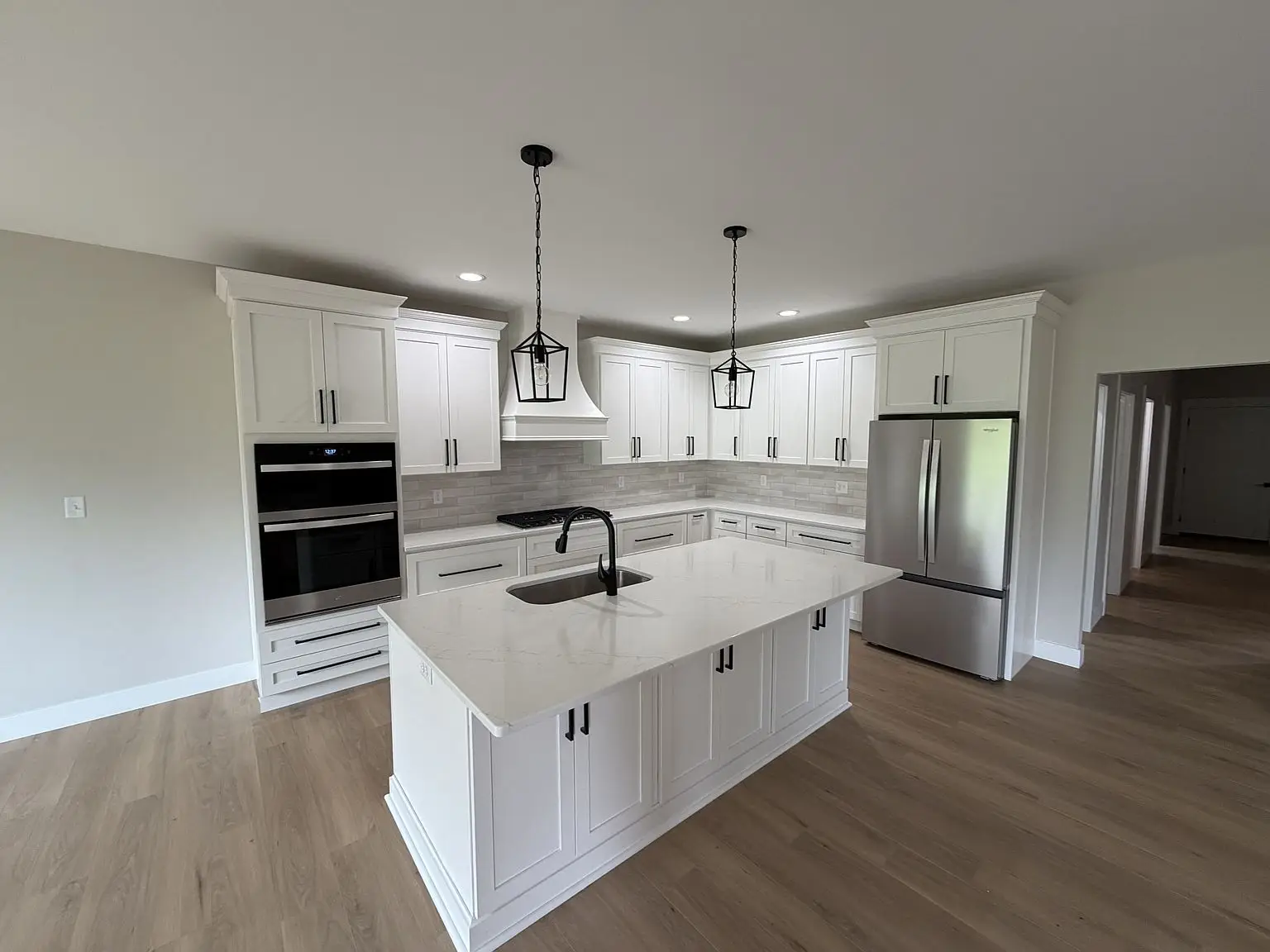 Modern kitchen with Robin floor plan, white cabinets, island, stainless appliances, wood flooring.