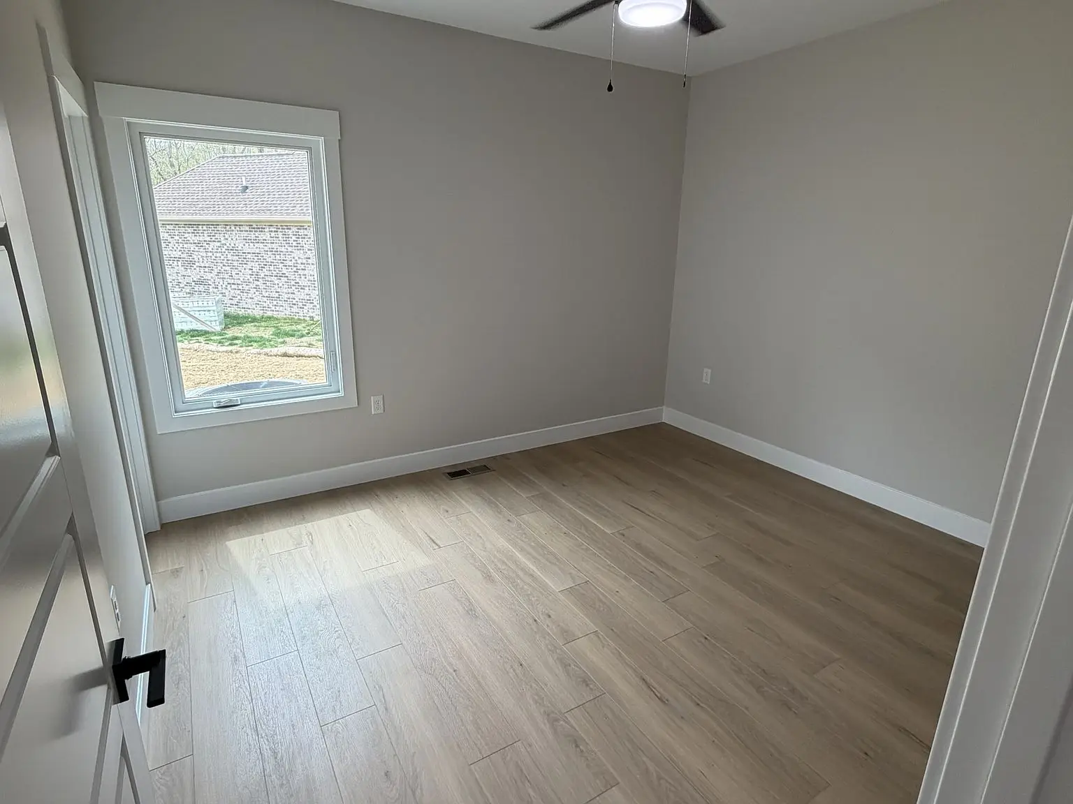 Empty room in the Robin floor plan with light wood floor, gray walls, and white trim.