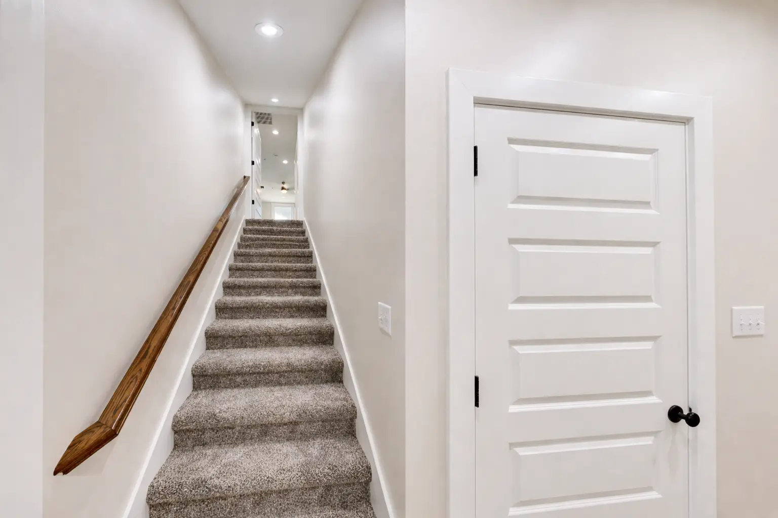 Carpeted staircase and white paneled door at Sophia by Chris Brown Homes, 5588 Lenox Dr.