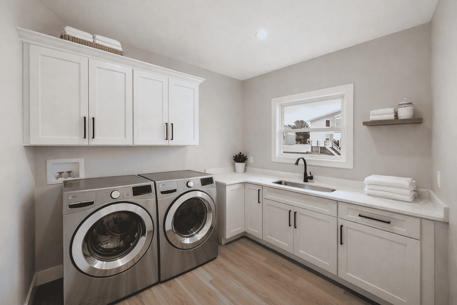 Modern laundry room with stainless steel appliances and white cabinets at 18800 Wicklow Way, Aurora.