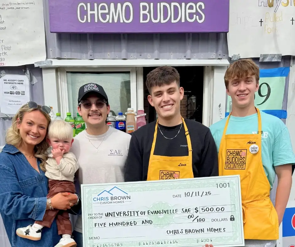 Five people smile with a $500 check in front of a Chemo Buddies booth, giving back to community.