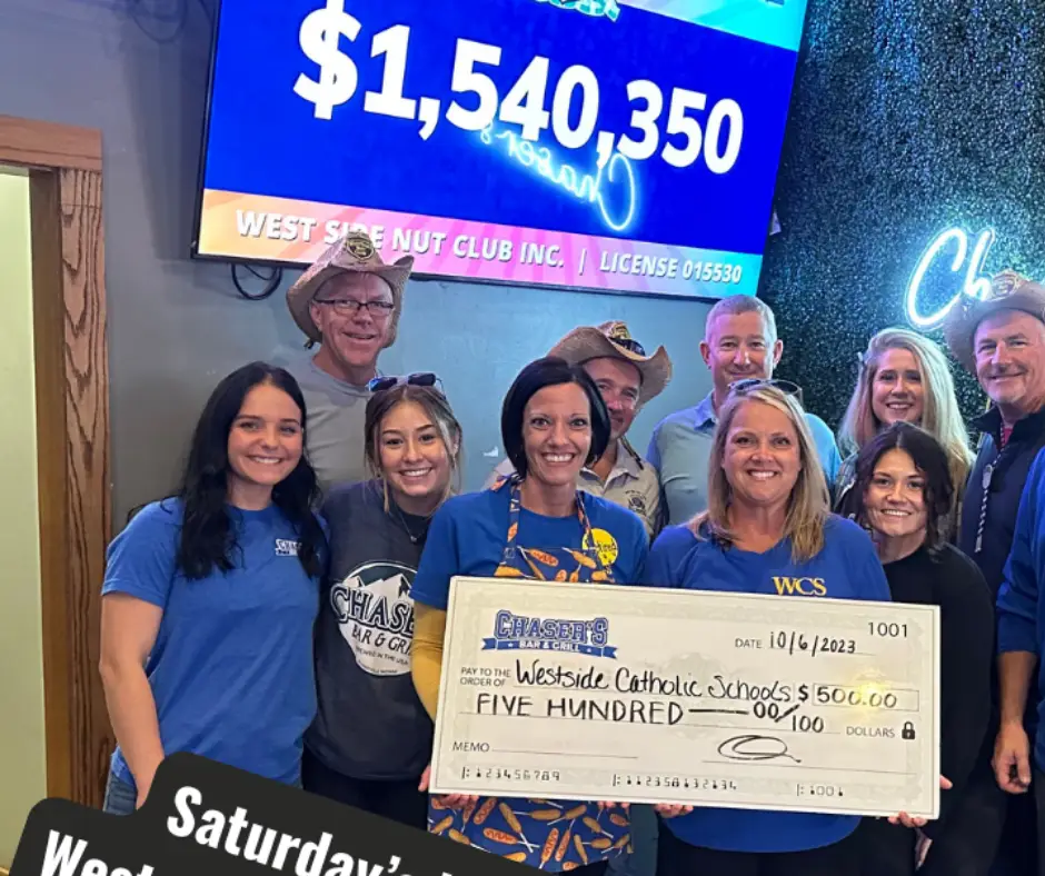 A group of people holds a large check for $500 to Westside Catholic Schools.