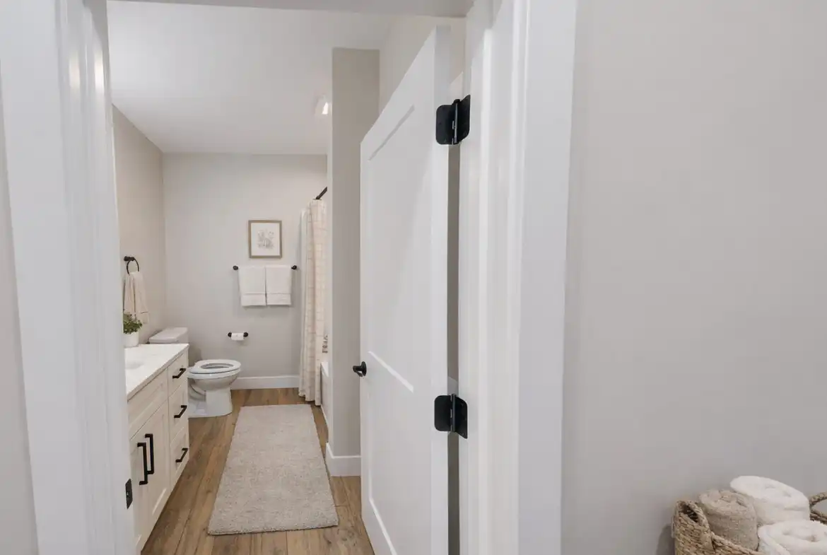 Leo-inspired modern bathroom with white vanity, black hardware, neutral decor, and striped shower curtain.