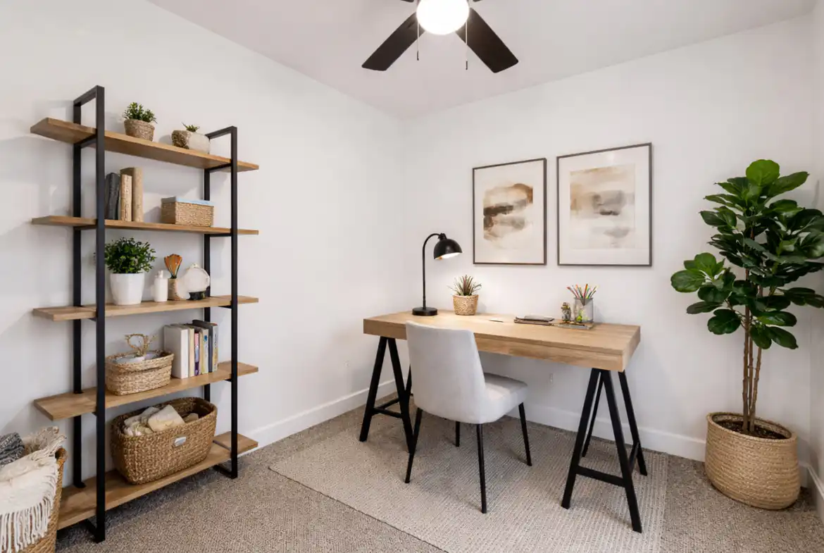 Minimalist Leo home office with warm wood desk, black shelving, woven baskets, and lush plants.