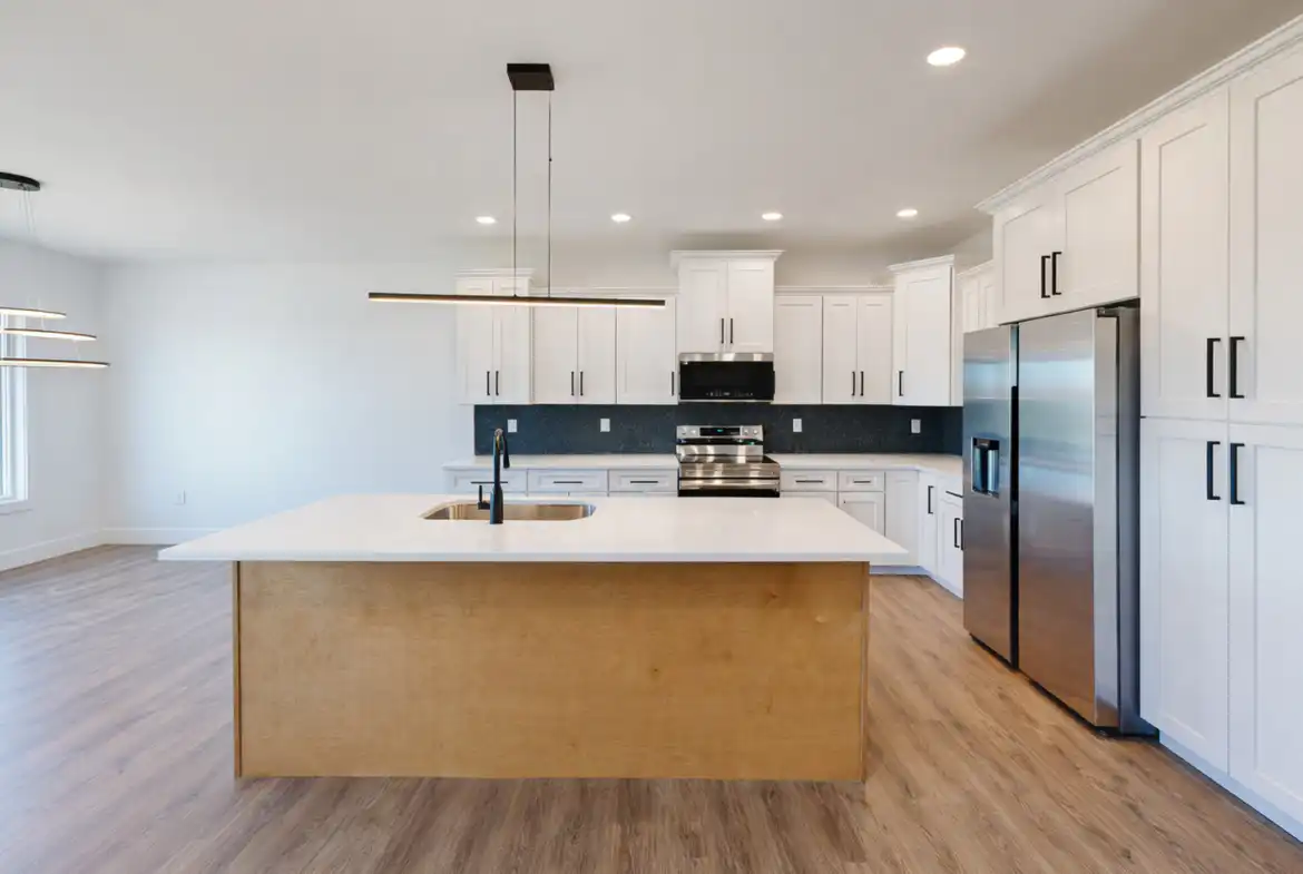Modern Leo kitchen with white cabinets, stainless appliances, and large wood island with sink.