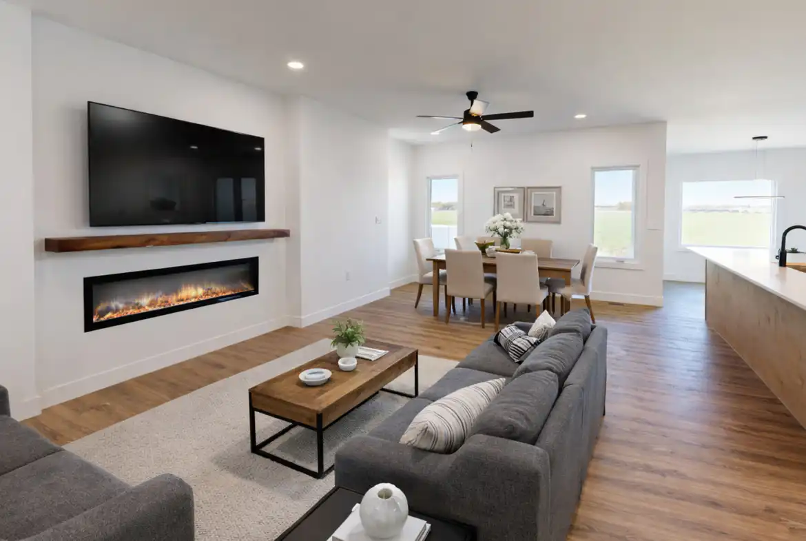 Leo-inspired open-concept living room with gray sofas, linear fireplace, dining area, and kitchen island.